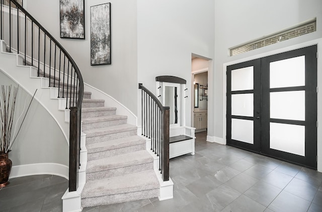 foyer entrance featuring stairs, marble finish floor, french doors, baseboards, and a high ceiling