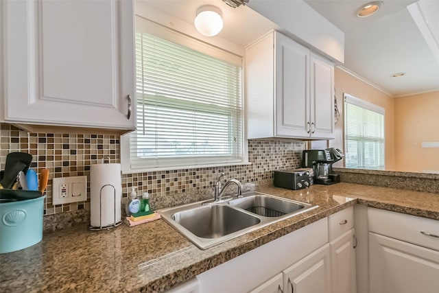kitchen featuring white cabinets, decorative backsplash, and a sink