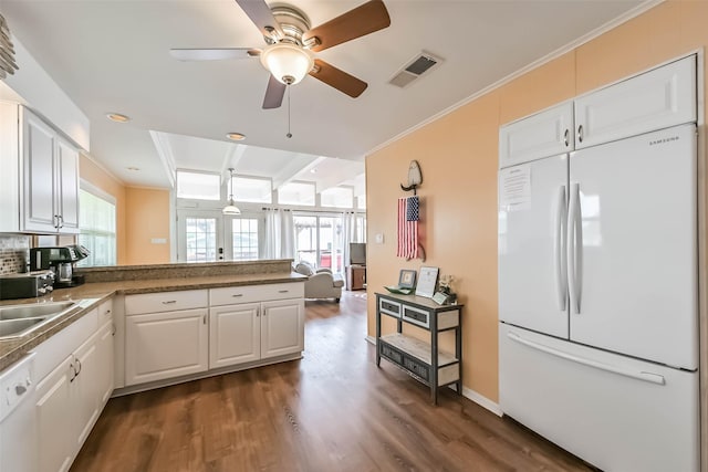 kitchen with a peninsula, dark wood finished floors, visible vents, white cabinetry, and white appliances
