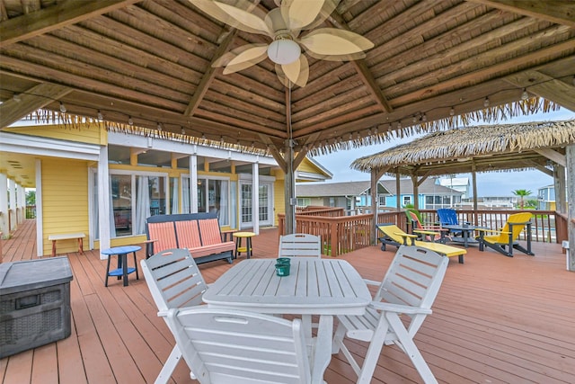 wooden terrace featuring a gazebo, outdoor dining space, and ceiling fan