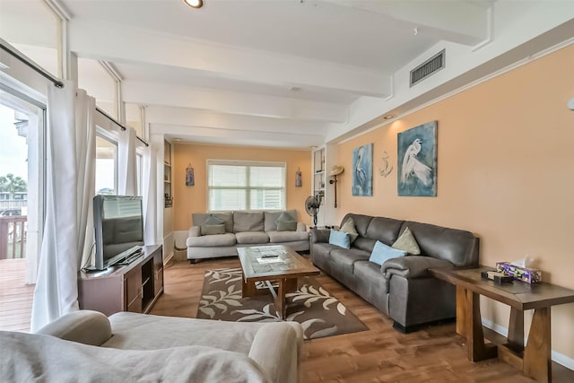 living room with wood finished floors, visible vents, and beam ceiling