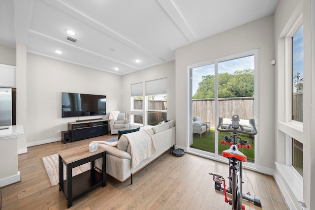 living room with light wood-style flooring, visible vents, beam ceiling, and a healthy amount of sunlight