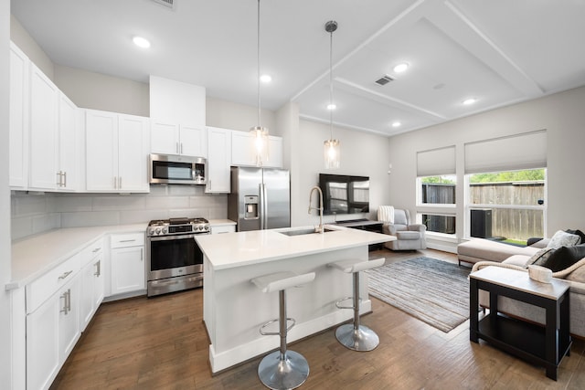 kitchen featuring stainless steel appliances, a sink, open floor plan, and backsplash