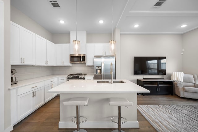 kitchen with open floor plan, backsplash, appliances with stainless steel finishes, and visible vents