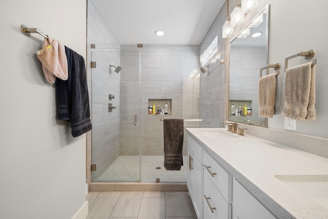 full bathroom featuring recessed lighting, double vanity, a shower stall, and a sink