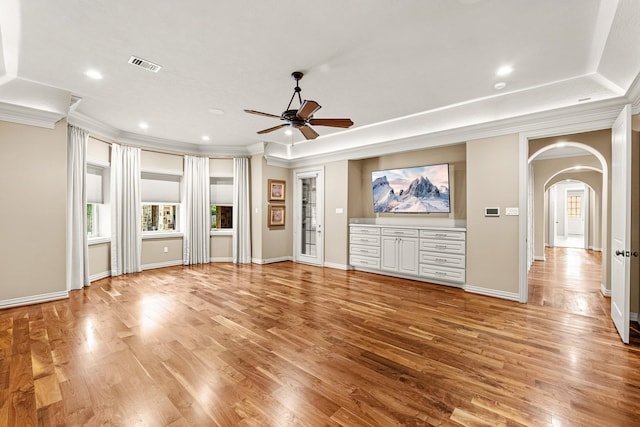28002 Whispering Maple Way, Spring, TX 77386 - unfurnished living room featuring arched walkways, ceiling fan, light wood-style flooring, crown molding, and baseboards