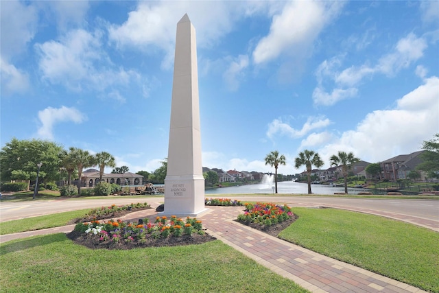 view of property's community with a residential view, a lawn, and a water view
