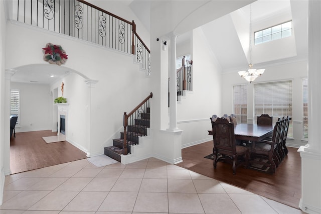 tiled dining space with a high ceiling, stairs, and ornate columns