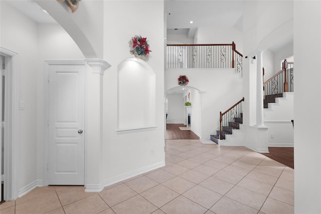 entrance foyer with arched walkways, a high ceiling, and light tile patterned flooring