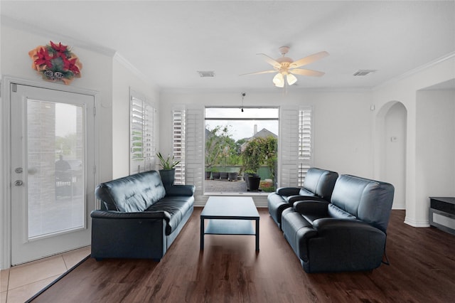 living area featuring arched walkways, visible vents, crown molding, and ceiling fan