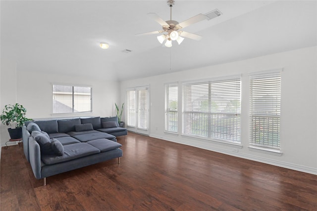 living area with lofted ceiling, baseboards, wood finished floors, and visible vents