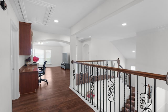 corridor featuring attic access, arched walkways, dark wood finished floors, baseboards, and recessed lighting