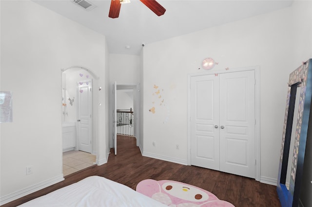 bedroom featuring wood finished floors, a closet, arched walkways, baseboards, and visible vents