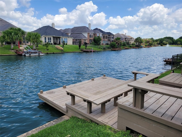 view of dock with a yard, a water view, and a residential view