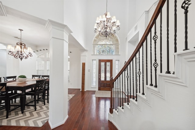 foyer with stairs, a notable chandelier, a towering ceiling, and plenty of natural light