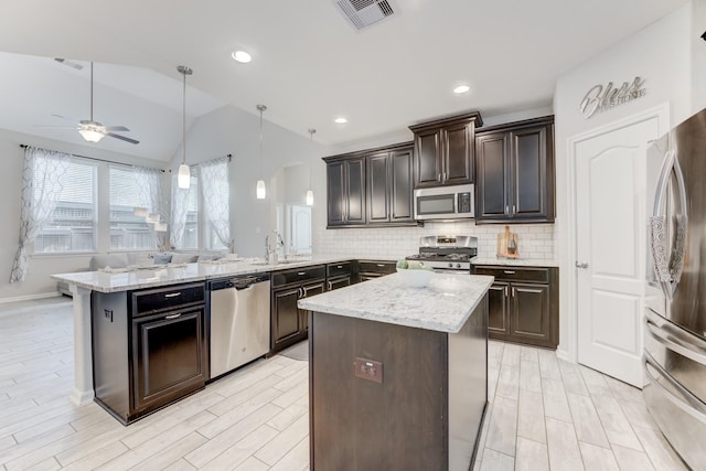 kitchen featuring a peninsula, vaulted ceiling, visible vents, backsplash, and appliances with stainless steel finishes