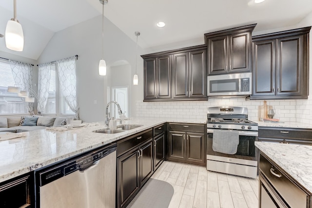kitchen with stainless steel appliances, a sink, vaulted ceiling, backsplash, and light stone countertops