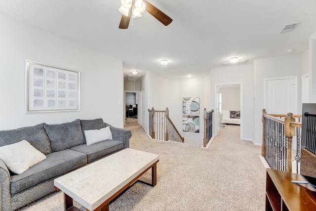 living room with attic access, light carpet, visible vents, and a ceiling fan