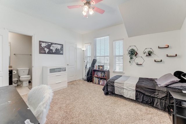 carpeted bedroom with ensuite bathroom and a ceiling fan