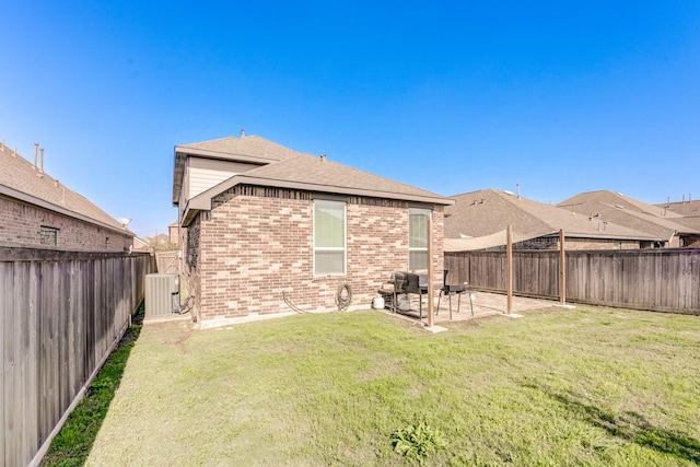 rear view of house featuring a lawn, a fenced backyard, brick siding, and a patio area