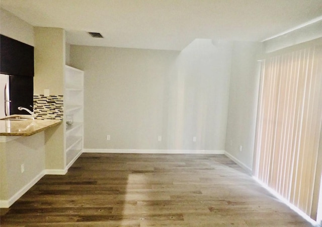 interior space featuring baseboards, wood finished floors, visible vents, and a sink