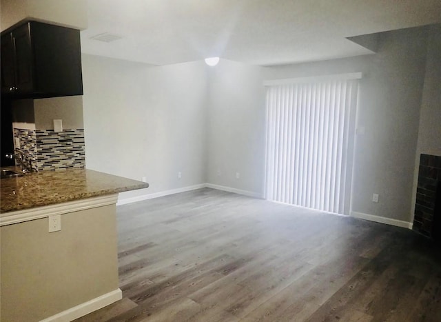 unfurnished living room with wood finished floors, baseboards, and a sink
