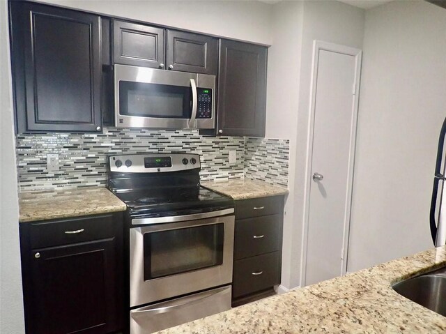 kitchen featuring backsplash, light stone countertops, and stainless steel appliances