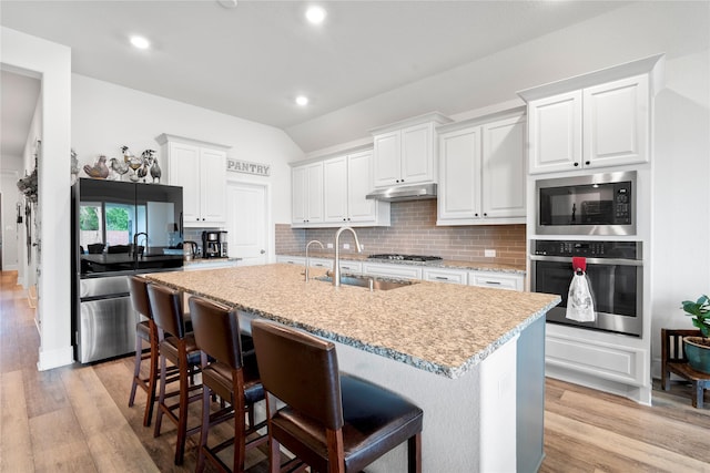 1818 Regent Mill Dr, Missouri City, TX 77459 - kitchen with stainless steel appliances, a sink, tasteful backsplash, light wood-style floors, and under cabinet range hood