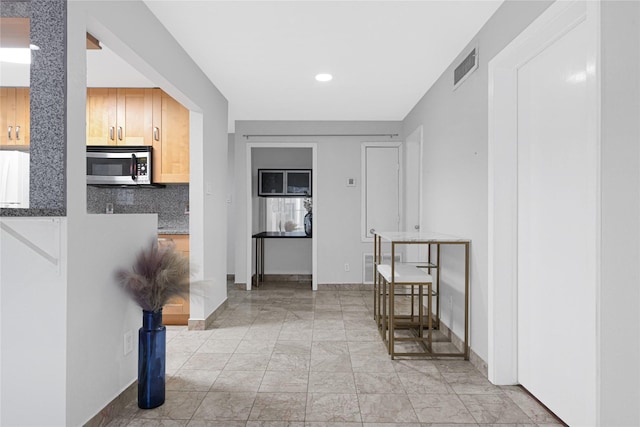hallway with baseboards, visible vents, recessed lighting, and marble finish floor