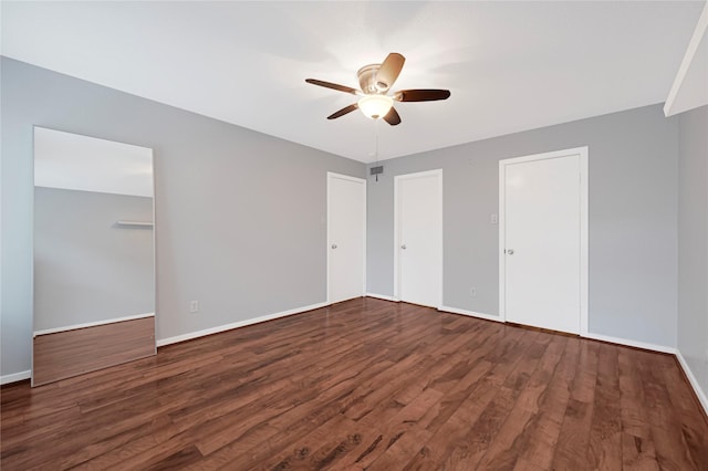 unfurnished bedroom with wood finished floors, two closets, ceiling fan, baseboards, and visible vents