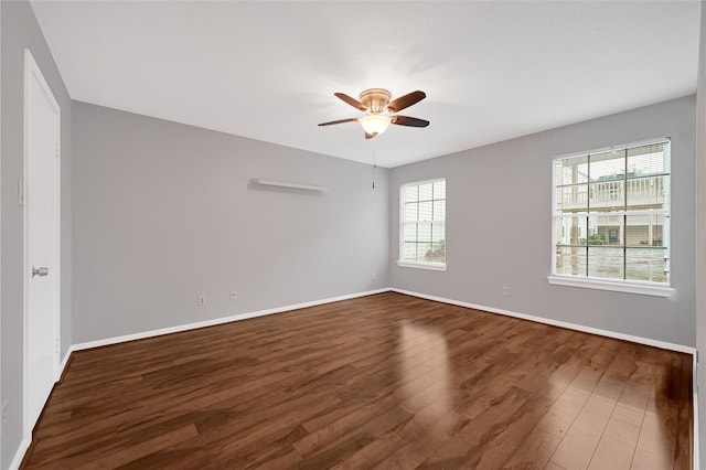 empty room featuring dark wood finished floors, baseboards, and ceiling fan