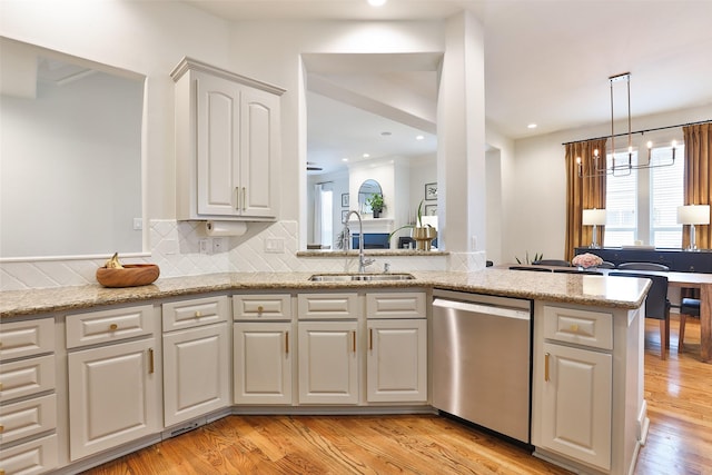kitchen featuring white cabinets, tasteful backsplash, a sink, dishwasher, and light wood-type flooring