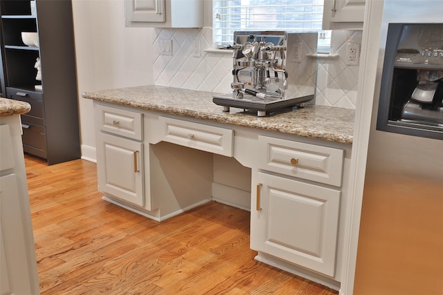kitchen with white cabinets, light stone counters, tasteful backsplash, and light wood-style floors