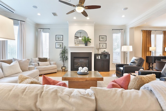 living area with plenty of natural light, ornamental molding, ceiling fan, and visible vents