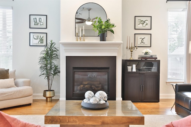 living room with ceiling fan, a tile fireplace, wood finished floors, and a wealth of natural light