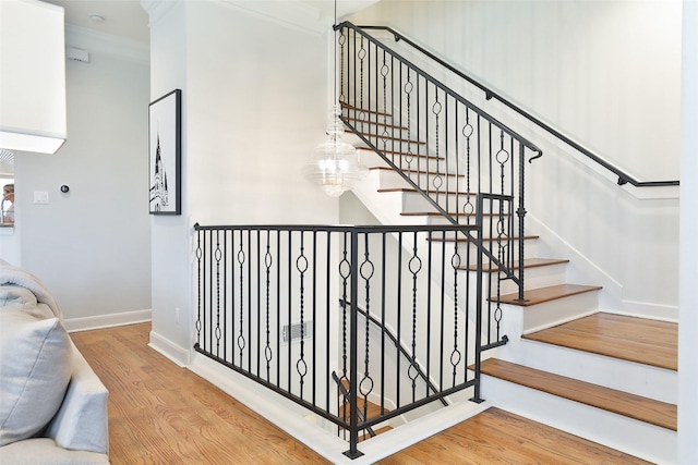 stairway featuring baseboards, crown molding, and wood finished floors