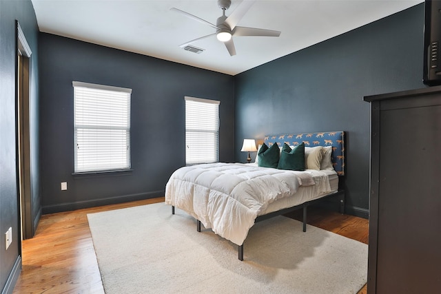 bedroom featuring baseboards, visible vents, multiple windows, and light wood-style floors