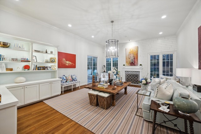 living room with wood finished floors, an inviting chandelier, recessed lighting, and ornamental molding