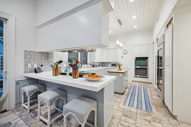 kitchen featuring decorative backsplash, a peninsula, white cabinetry, and a breakfast bar