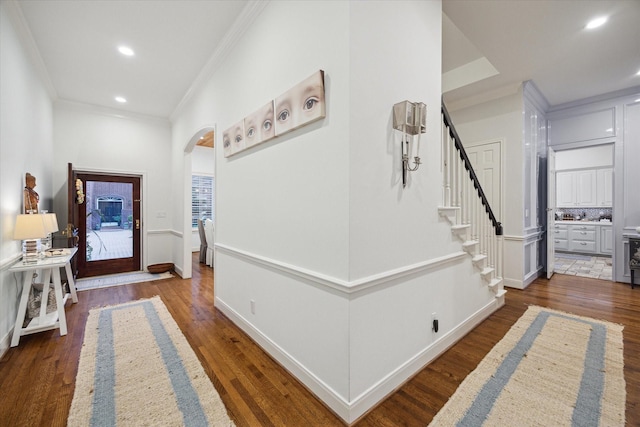 hall featuring wood finished floors, arched walkways, stairway, and crown molding