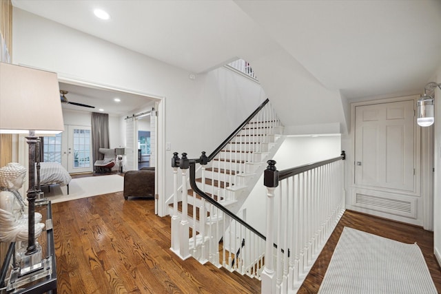 stairs featuring wood finished floors and recessed lighting