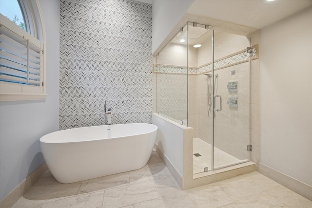 bathroom featuring a shower stall, tile walls, marble finish floor, a freestanding bath, and baseboards