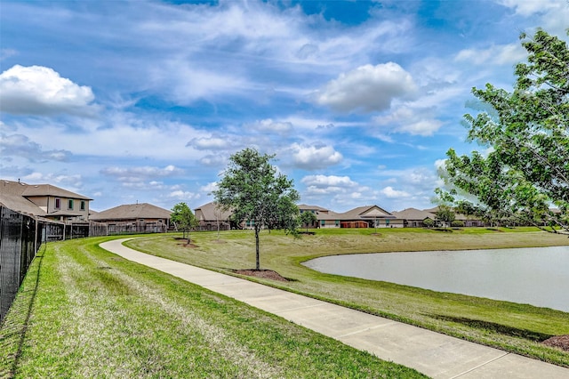 view of yard featuring fence, a residential view, and a water view
