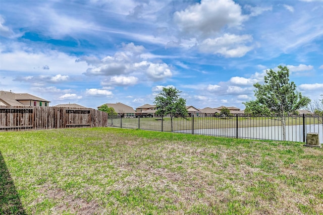 view of yard featuring a residential view, a water view, and fence