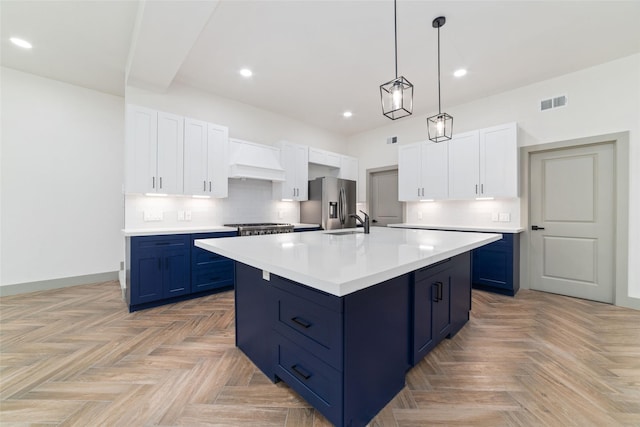 kitchen with blue cabinetry, premium range hood, stainless steel fridge, backsplash, and recessed lighting