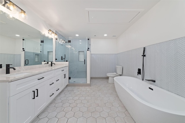 11931 S Red Cedar Cir, The Woodlands, TX 77380 - bathroom with double vanity, a shower stall, a freestanding tub, toilet, and wainscoting