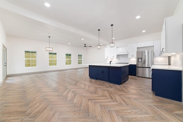 11931 S Red Cedar Cir, The Woodlands, TX 77380 - kitchen with stainless steel fridge with ice dispenser, blue cabinetry, light countertops, open floor plan, and a kitchen island with sink