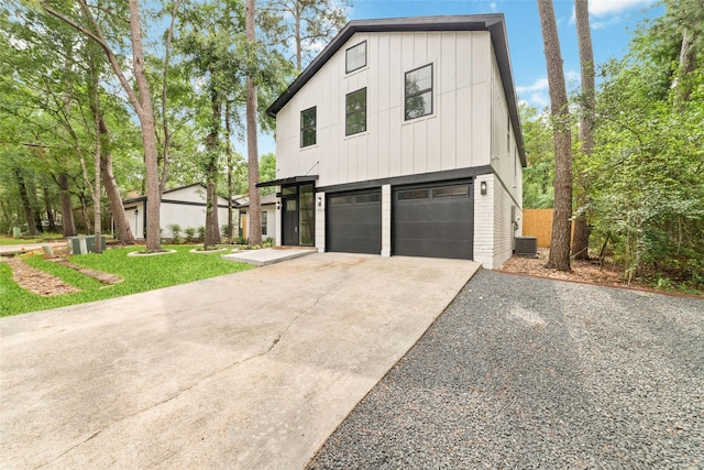 11931 S Red Cedar Cir, The Woodlands, TX 77380 - view of front of house featuring driveway, an attached garage, board and batten siding, central AC, and a front lawn