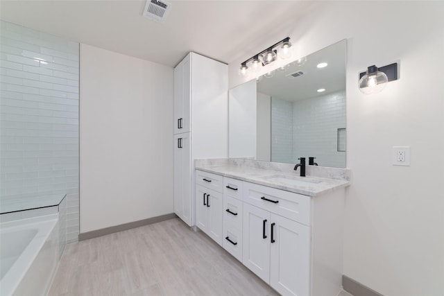 11931 S Red Cedar Cir, The Woodlands, TX 77380 - bathroom with vanity, a tub to relax in, wood finished floors, and baseboards