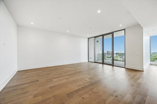 unfurnished room with expansive windows, recessed lighting, and wood finished floors